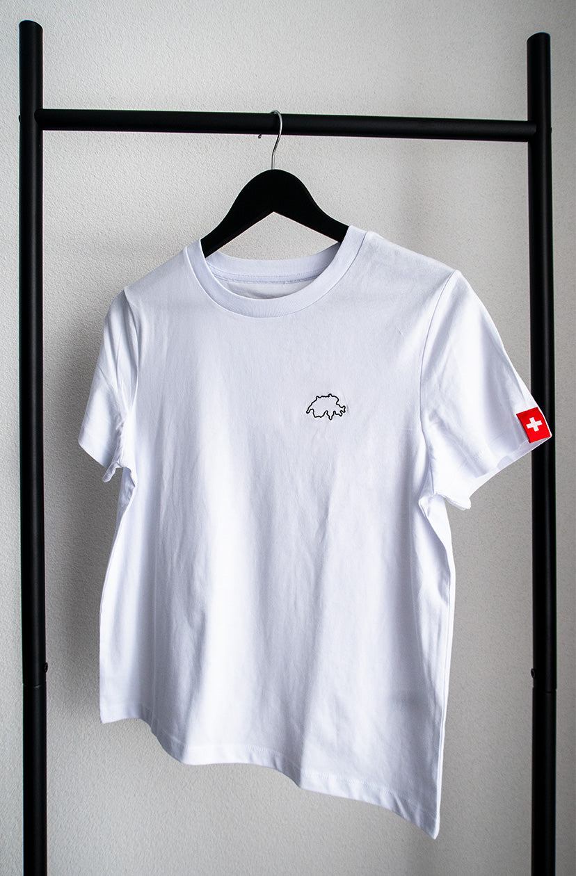 Weisses Twelvetia Damen-T-Shirt mit schwarz gestickter Schweizer Landesumrandung auf linker Brust und Schweizer-Flagge-Etikett am linken Ärmel. Hängend an schwarzem Bügel vor weißer Wand.