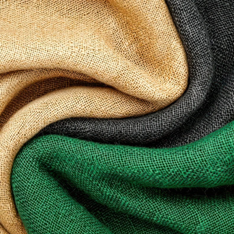 Drei Stoffe in den Farben Grün, Beige und Grau sind ineinander verdreht.